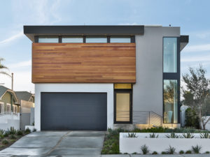 Elevation of a modern house from the street. Shows the garage door, front entrance, and the driveway.