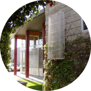 View of side of a office complex. Includes a covered exterior ladder attached to the brick wall, as well as multiple red metal columns extending from the floor to the ceiling.