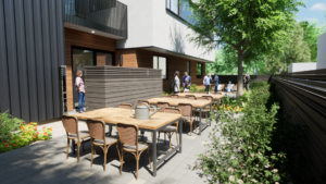 Rending of a community area in a modern apartment complex. Trees and flowers surround multiple wooden tables and chairs, with people gathered in an open area in the background of the rendering.