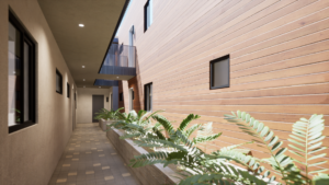 Rendering of a courtyard in a modern apartment complex. A raised plant bed borders a wooden facade wall, with lights built into the above walkways shining down onto a tiled floor and stucco walls.