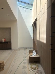 Construction photo with a few wires and boxes laying on the ground within a white wall and floor protection covered room.