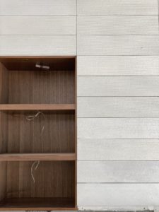 Photo of an empty wooden cabinet embedded within a gray brick wall.