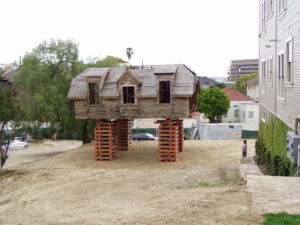 Photo of construction work on the second floor of a modern house. With no first floor present, wooden turning blanks are stacked to hoist the second floor of the building above the ground