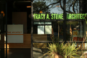 Building entrance adorned with company logo and address on window. Two potted plants rest outside, while the front desk is visible through the open door.